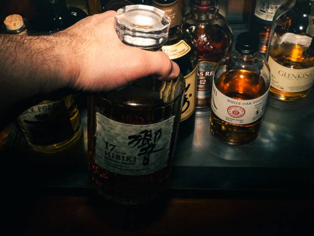 Mann nimmt eine Flasche Whiskey aus dem Schrank